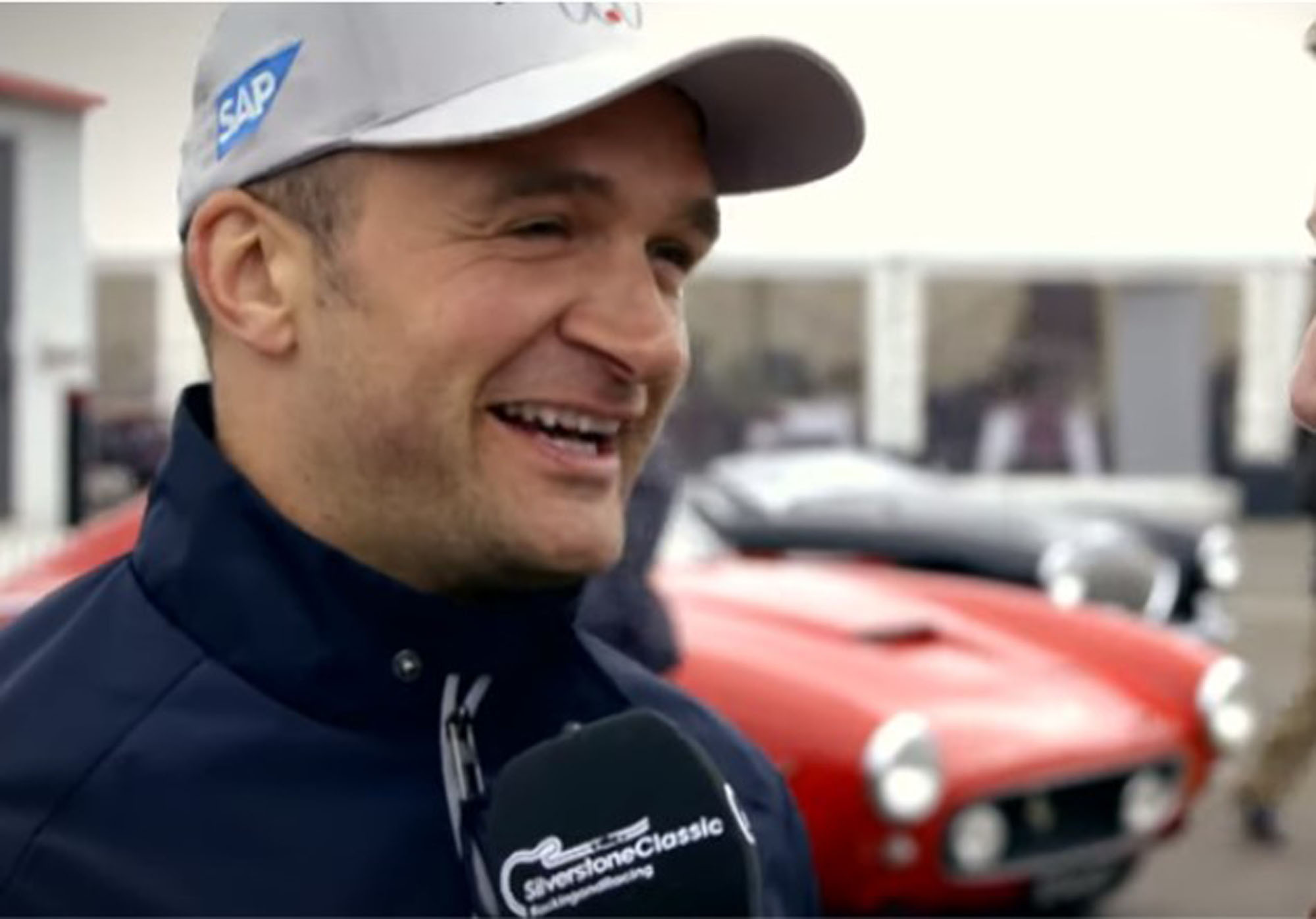 Colin Turkington being interviewed at The Classic at Silverstone in front of a red classic car