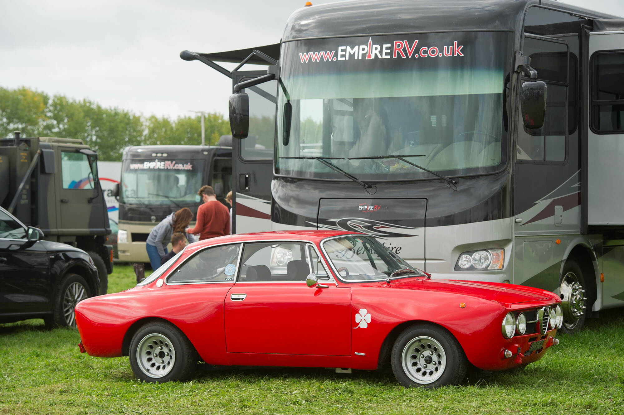 An Empire RV Motorhome parcked behind a red classic car