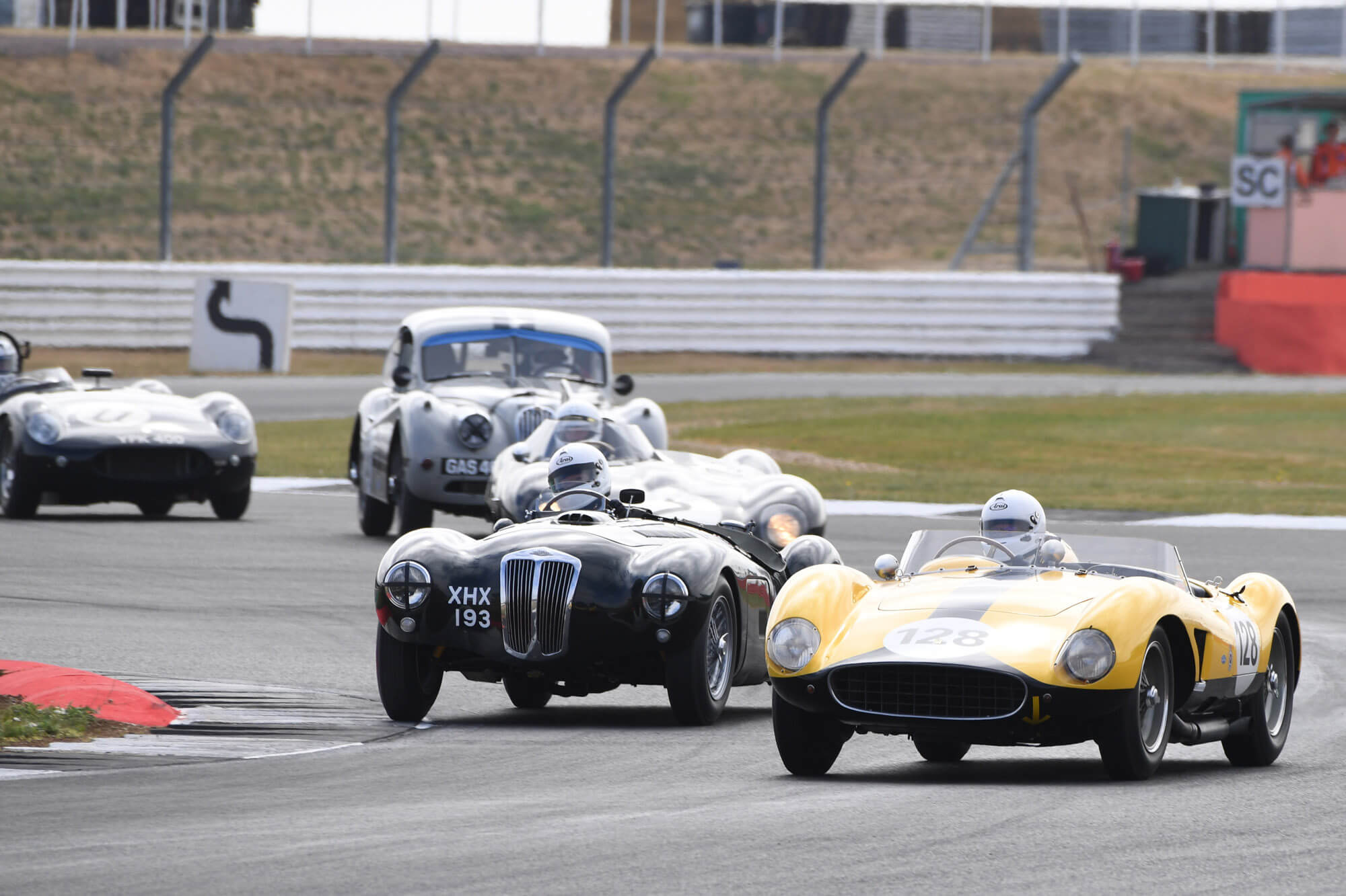 Four classic cars competing on track in the Royal Automobile Club Woodcote and Stirling Moss trophy at The Classic at Silverstone 