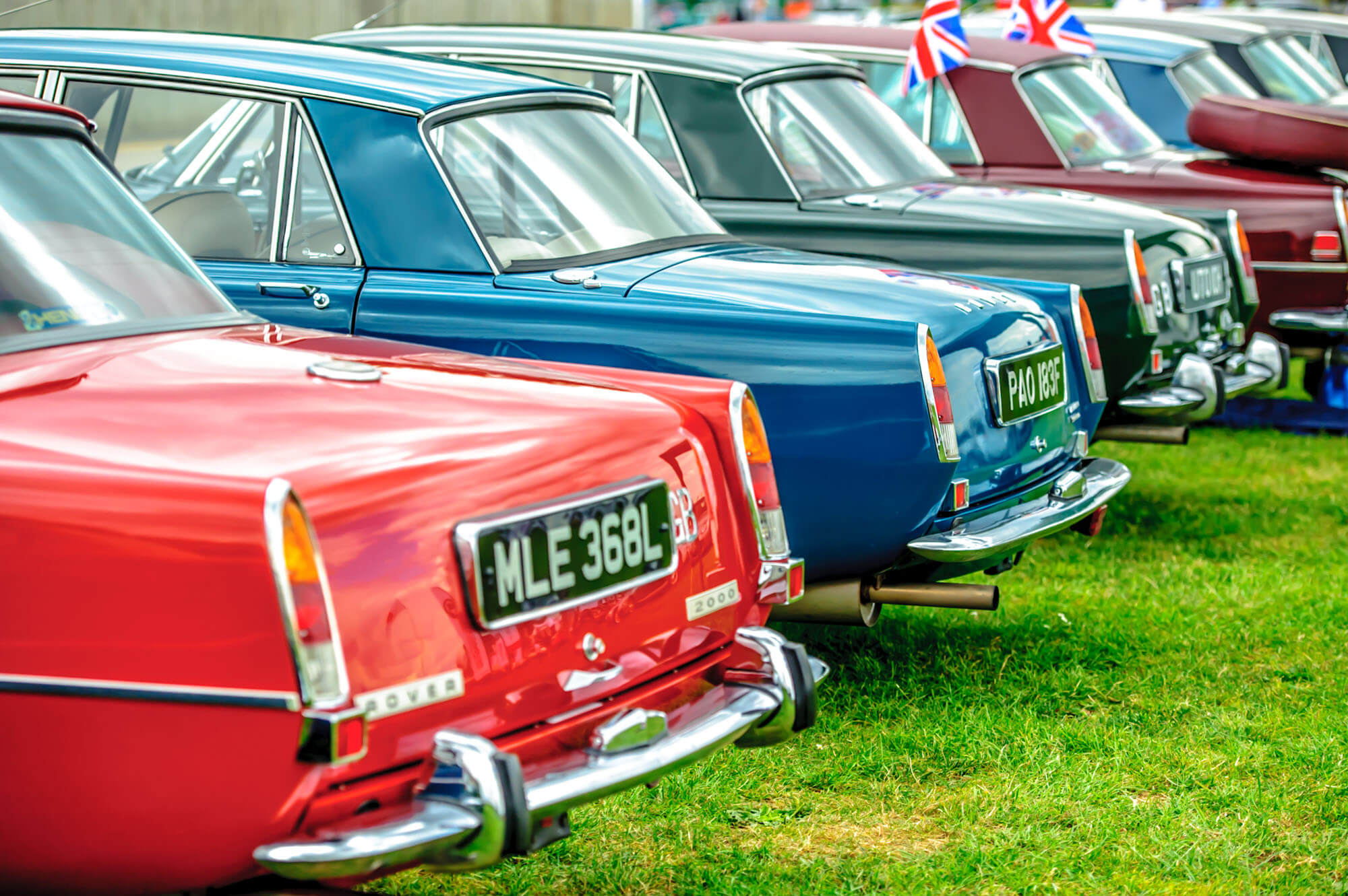A line-up of brightly coloured classic cars on display as part of a Car Club at The Classic at Silverstone