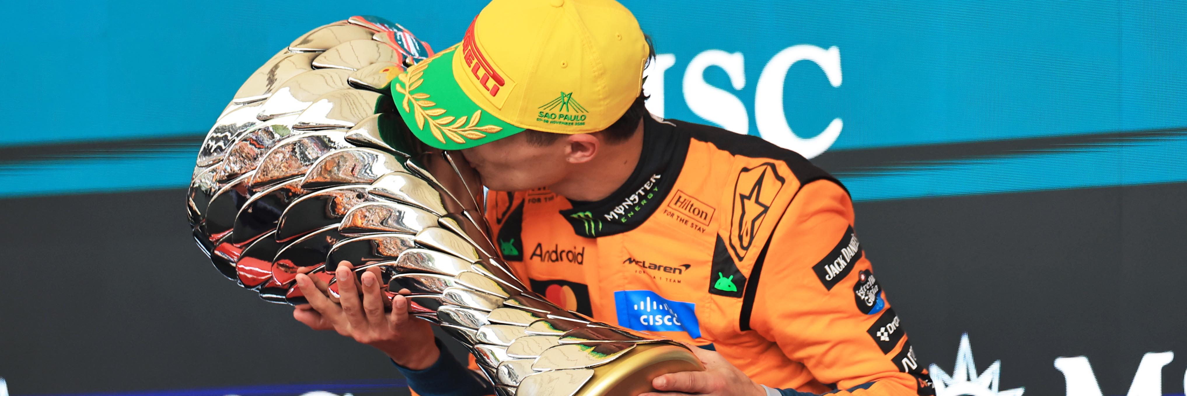 Lando Norris kisses an F1 trophy on the Sao Paulo podium