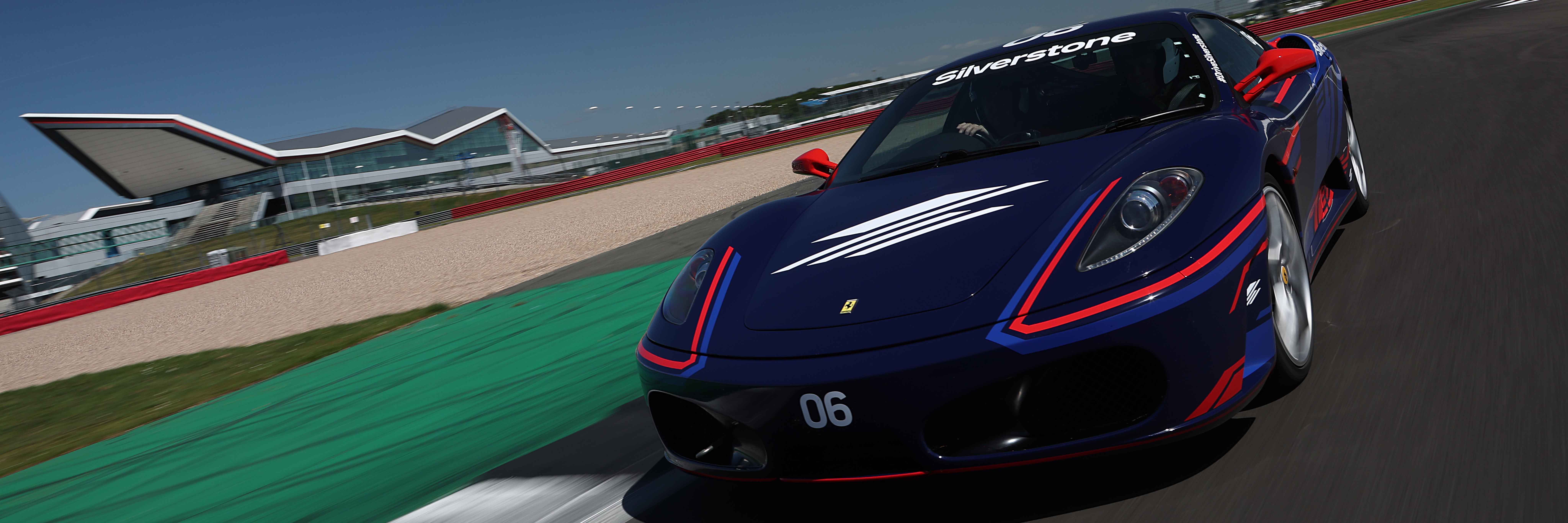 A Ferrari F430 at Silverstone with the iconic Wing building in the background