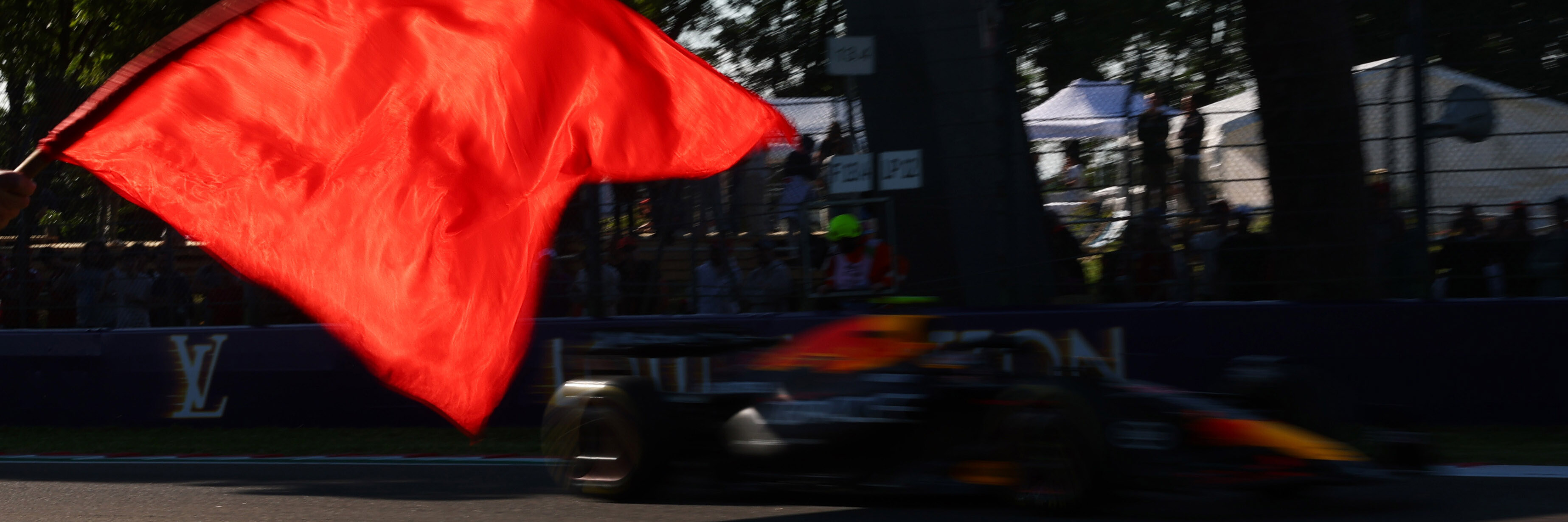 A red flag being waved at a red bull F1 car