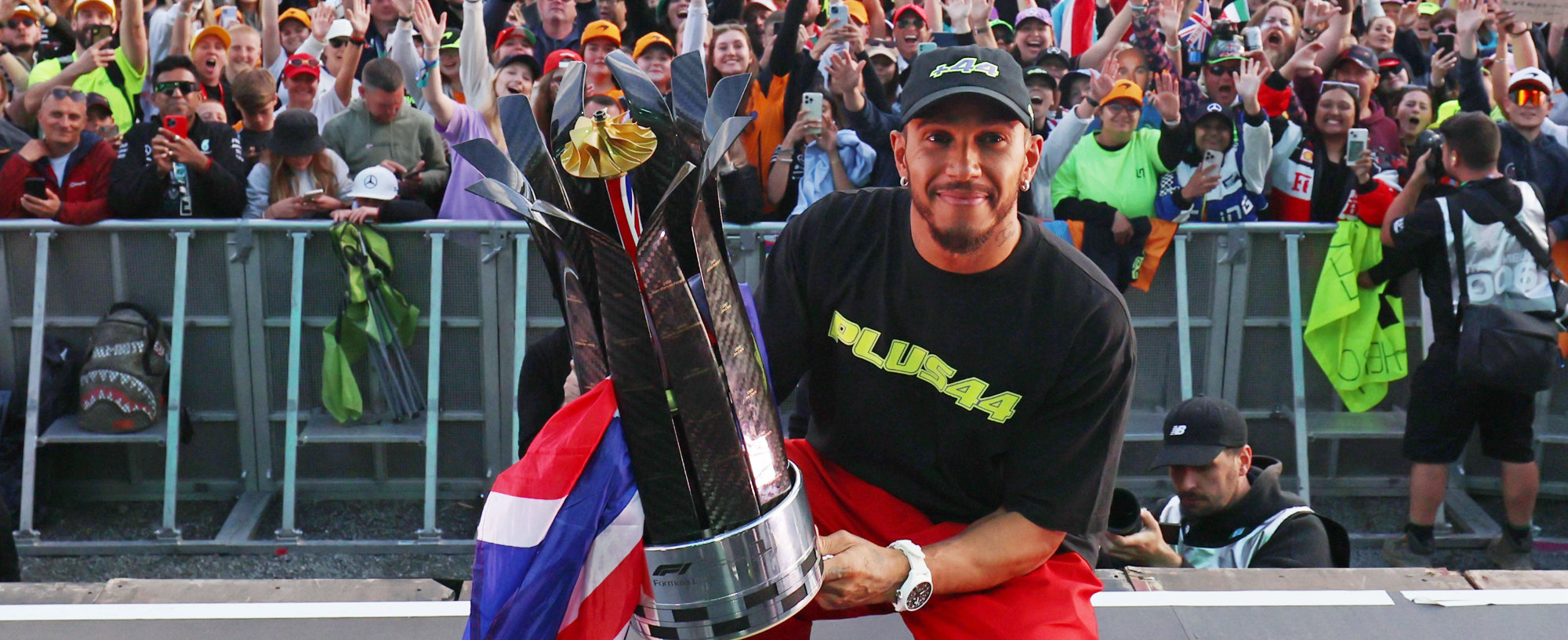 Sir Lewis Hamilton poses with the Silverstone crowd, holding his trophy after a historic ninth win at the British Grand Prix.
