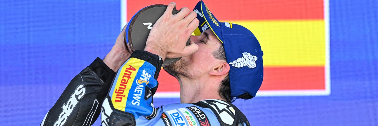 alex marquez kisses a trophy standing on the podium