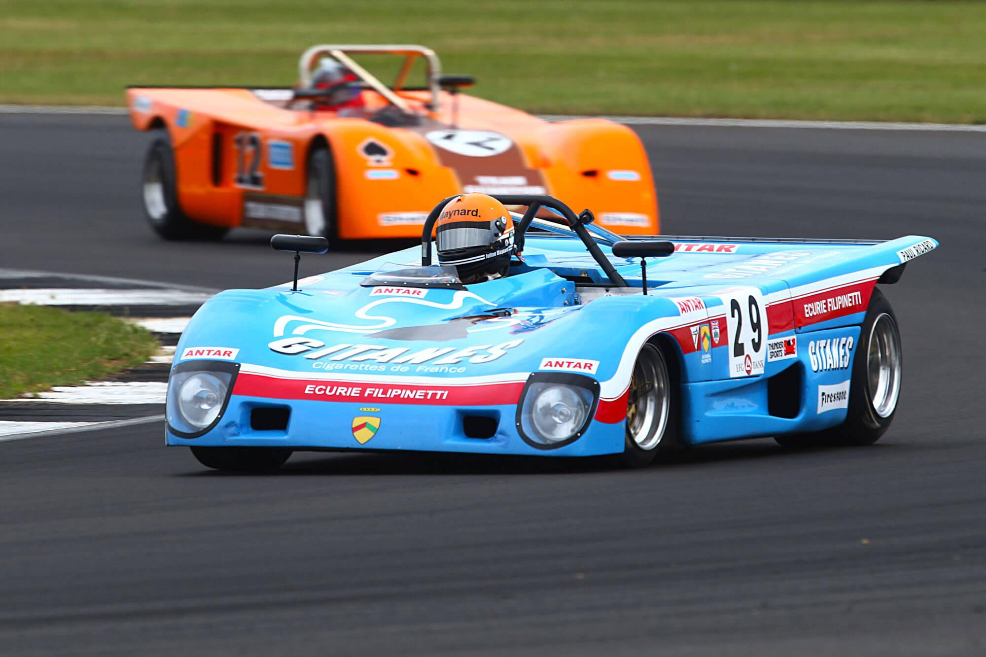 Two classic cars racing round a corner in the HSCC Thundersports grid at The Classic at Silverstone