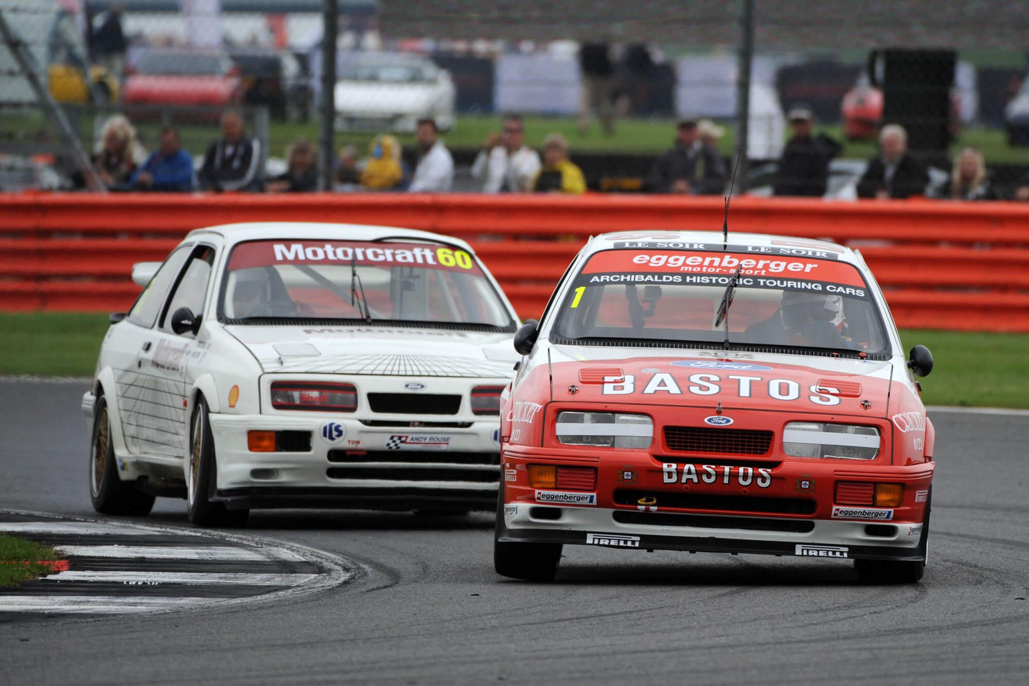 Two classic cars racing round a corner in the Historic Touring Car Challenge at The Classic at Silverstone