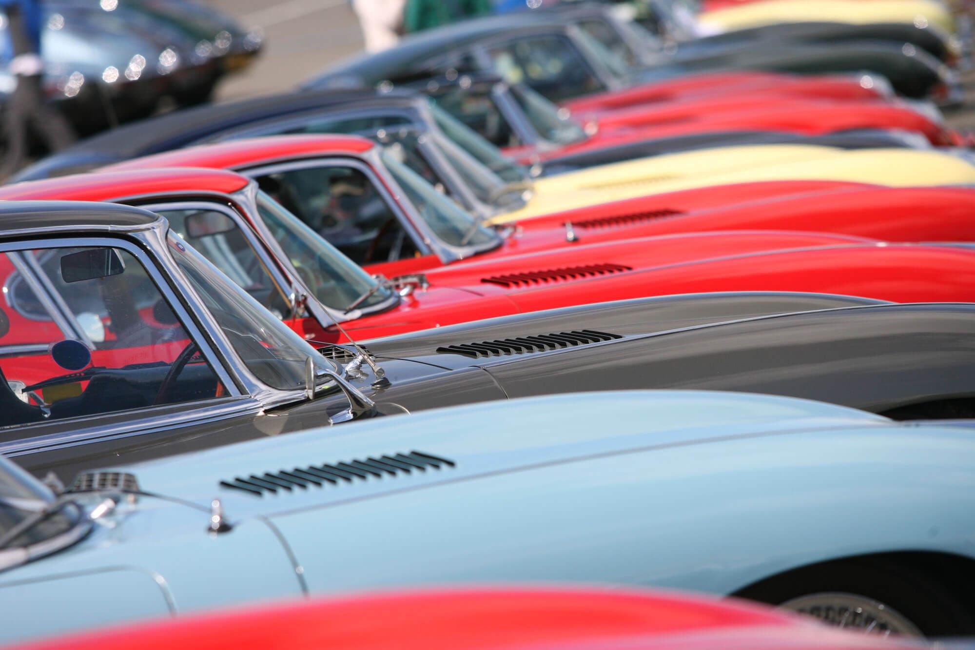 A line-up of brightly coloured classic cars displayed as part of a Car Club at The Classic at Silverstone