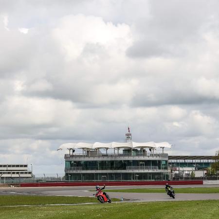 Riders on track at Silverstone. The BRDC clubhouse is visible in the background
